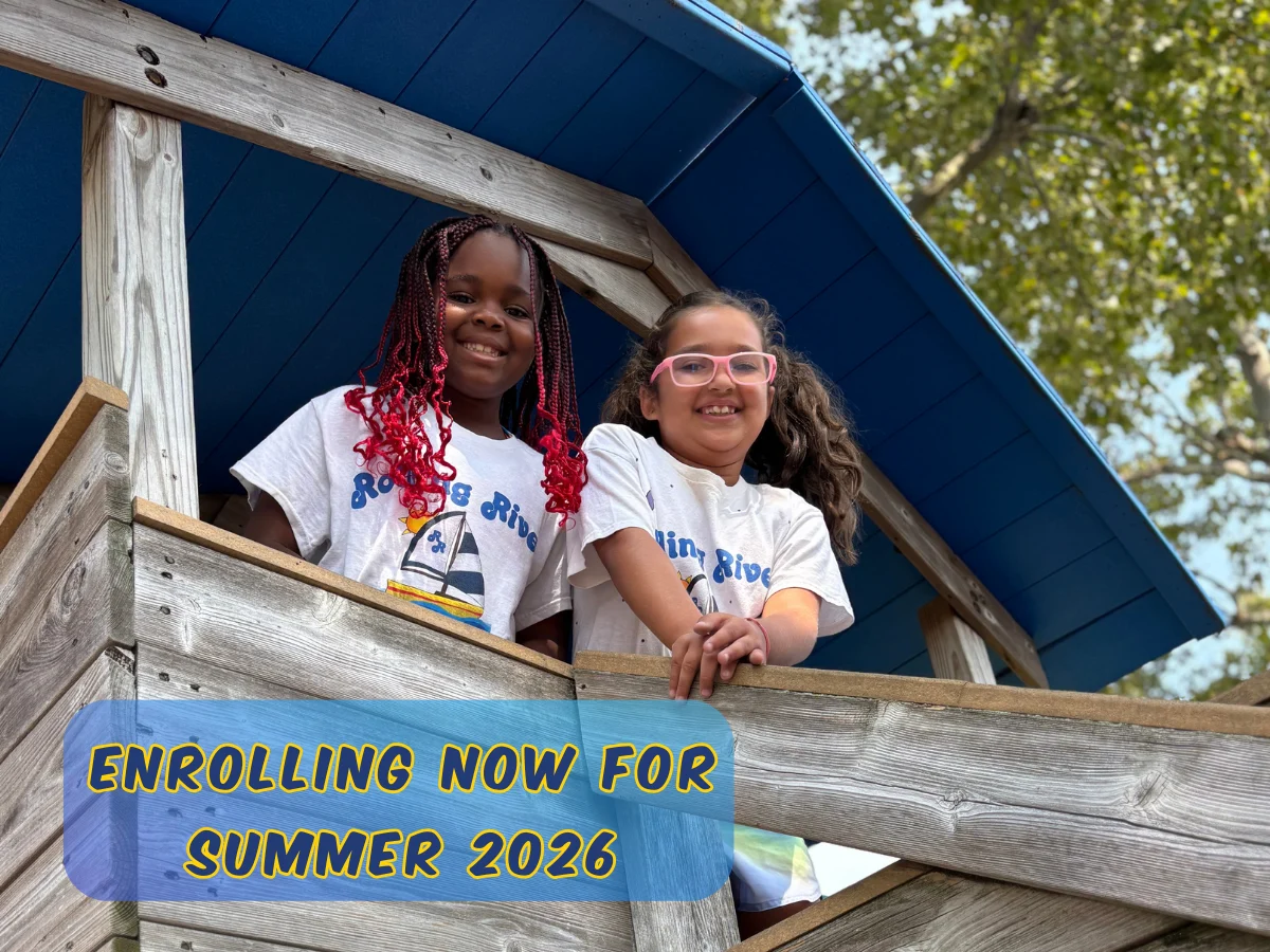 Two children smiling from a wooden play structure at Rolling River Day Camp during summer activities.