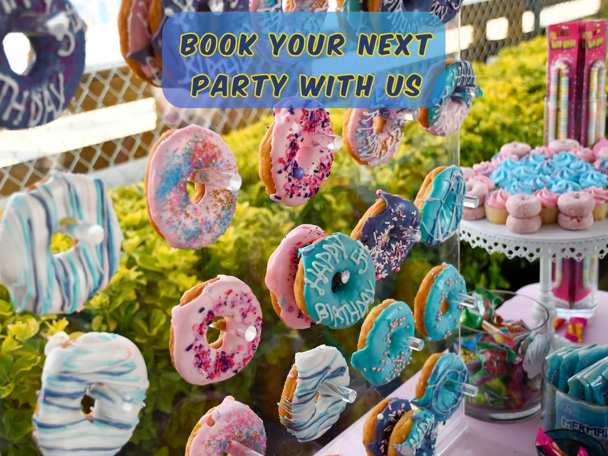 Colorful birthday donuts decorated with icing and sprinkles displayed at a Rolling River Day Camp party setup