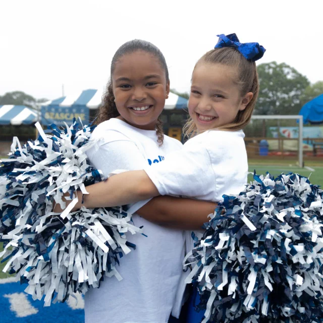 Two camper cheerleaders giving each other a hug.