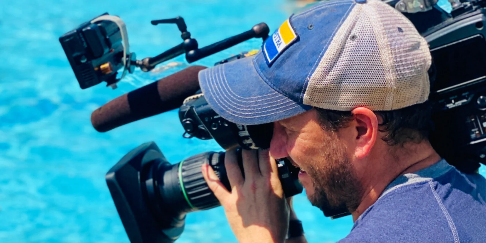 A man holding a camera at a pool.