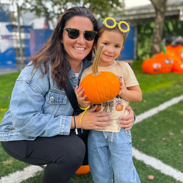 A camper holding a pumpkin alongside a parent.