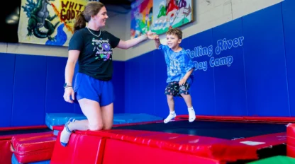 A camp counselor and camper on a trampoline.
