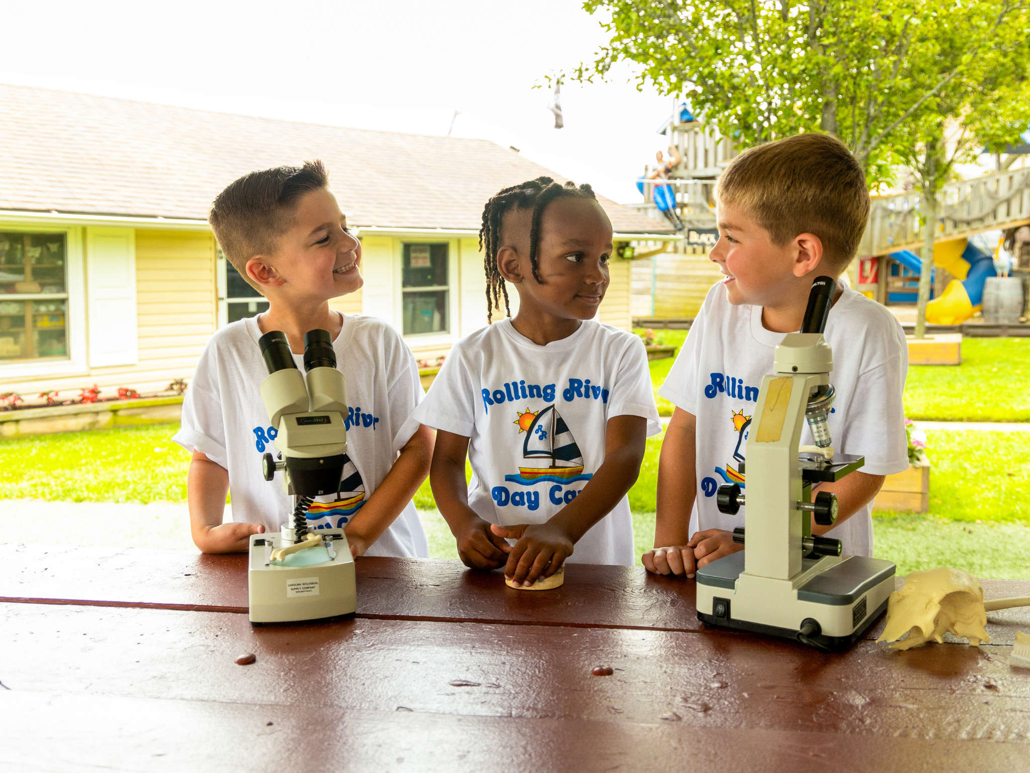 Three campers using microscopes.