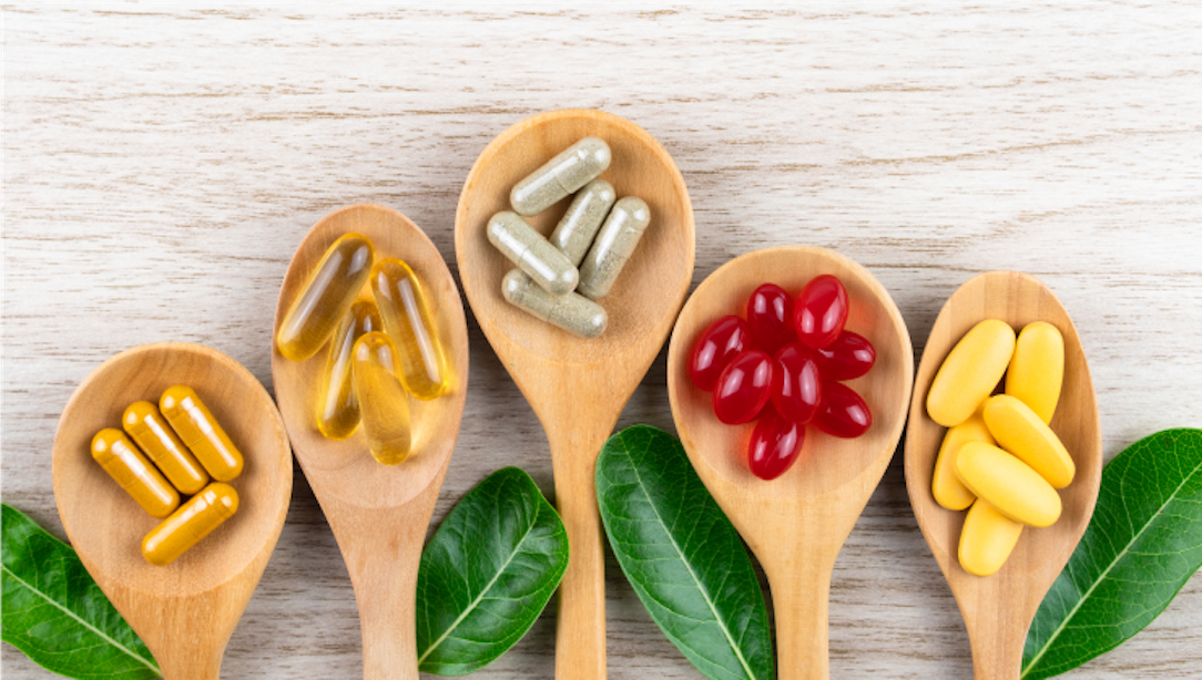 5 wooden spoons lined up in a row with different supplements in each.