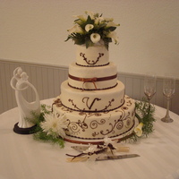Sandra's Dream Wedding Cake Smooth frosted buttercream cake. Chocolate brown scroll and monogram work. Brown ribbon. Fresh flowers on top...not done by me. This cake...