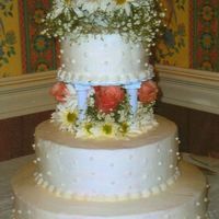 Simple Flowers And Dots Three tier with butter cream icing. Real Flowers.