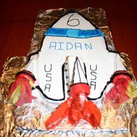 Rocket Cake Shape is cut from a sheet cake. Base for side and center "engines" are cut from the unused cake pieces. "Engines" are...