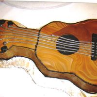 Kilkenny.jpg iced in chocolate bd with marbelized fondant on top to create wood grain. mixed silver lustre with piping gel for the strings