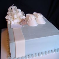 Package Baby Shower Cake White cake with raspberry mousse filling and buttercream frosting, gumpaste bow, booties and bear.