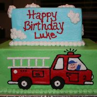 Fire Truck Cake 10 in and 8 in square iced in buttercream, fire truck on front, fire hydrants and tree on back, and firefighters on the sides putting out...