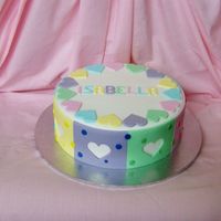 Isabella's 10Th Birthday 9 inch caramel mud cake covered in white fondx with fondant panels and hearts cut out. Inspired from a design in an old wilton book....