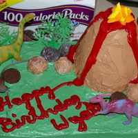 Dino Cake With Volcano Take 1 Decorated in buttercream icing. Volcano make out of RKT. Red lava is sparkle gel, fire is buttercream icing. Rocks made out of donut holes...