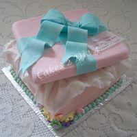 What's In The Box? Gift box cake. Cake is chocolate covered in chocolate buttercream icing. Tissue is fondant. Lid and bow is gumpaste. Gift tag is rice paper...