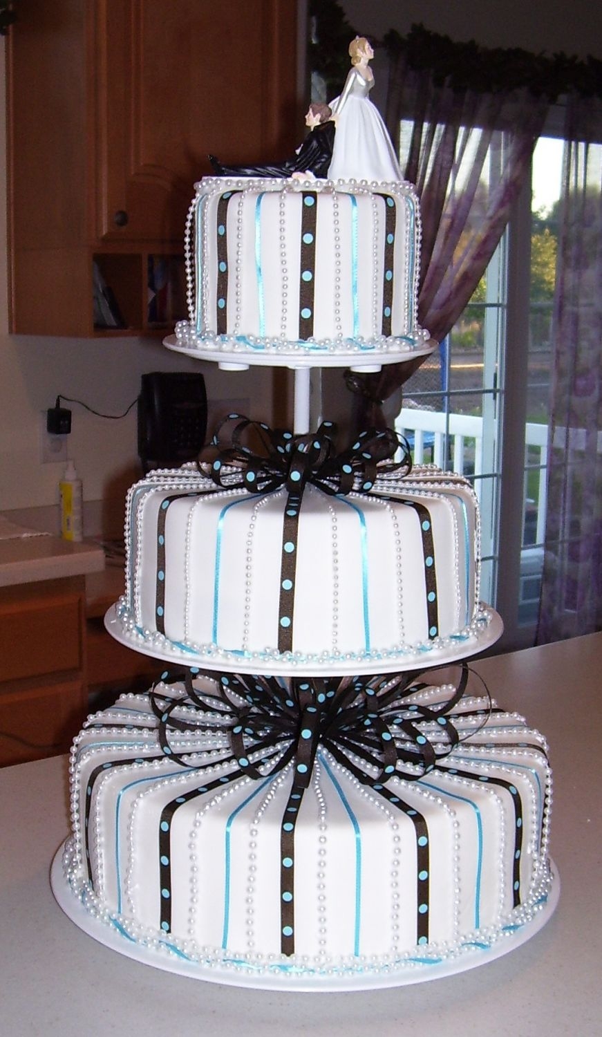 Blue And Brown Wedding Chocolate cake covered with fondant with blue and brown ribbons. Pearls between ribbons.