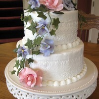 White Velvet White Chocolate cake with pecan/caramel filling in bottom layer and raspberry mousse filling in top layer. Gumpaste/fondant flowers and ivy...