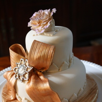 Golden Birthday Cake Made for a friends birthday, this mini cake is Lemon Raspberry covered in fondant. Flower, ribbon & brooch are all made of gum paste.