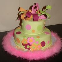 Pretty Polkadot Cake covered in MMF with different size round cutouts, different size blossom cutouts. Wacky bow and added boa to finish off trim.