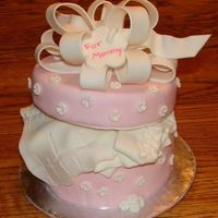 Pretty Present MMF covered 6" cake. Fondant covered 6" styrofoam lid. Fondant embossed flowers, handmade fondant bow and baby clothes.