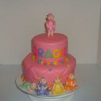Baby Princess 1St Birthday Fondant covered cake with flower border and accents. Five fondant babies with dresses and dusted with luster dust.
