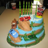Cars Cruising Oval pan set, iced with blue pastry pride and brown fondant hills border. fondant boulders covered on brown fondant as well to make it look...