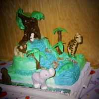 1St Try At A Jungle Theme Animals are molded in chocolate, large tree and rocks are candy clay, small trees are cookies covered in chocolate. Rest is buttercream.