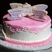 Teaparty Buttercream icing with pink airbrushing for table cloth. Sugar cookies on top with Royal icing and fondant .