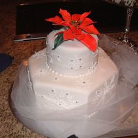 Snowflakes A fondant covered cake- 2 tier. Royal icng piped snowflakes and gumpaste poinsettia.