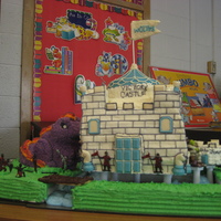 Road To Victory Castle for my daughter's class. All buttercream icing. Top tower fondant. Whipping cream water. One side are plastic soldiers fighting...
