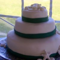 Fondant And Shells Fondant covered white cake with lemon and blackberry filling. Fondant shells and emerald green ribbon.