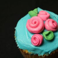 Rosebud Cupcake butter yellow cupcake w/ buttercream frosting in Teal. Satin Ice ribbon roses on top.