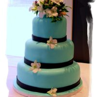 Sea Blue Turquoise fondant with a chocolate fondant ribbon and fresh white orchid topper.