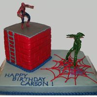 Spiderman With Building And Green Goblin Buttercream icing with a wooden dowel used to make brick impressions on building. Figures are toys.