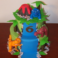 Dinosaur Cake What a fun cake. Iced in buttercream, everything else made out of fondant. I used chocolate rocks around the cake.