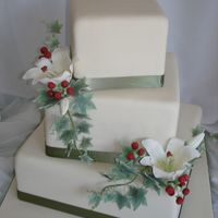 124346882539293.jpg Hazelnut cake with hazelnut BC filling. Gumpaste lilies, hypericum berries and ivy. Satin ribbon.