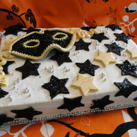 Masquerade Cake a black and white masquerade cake with gold highlights. The mask is gumpaste covered with edible glitter.