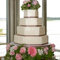 Floral Hexagons 4 tier hexagons, buttercream icing with fabric ribbon. Cake is elevated on a styrofoam cake dummy that has flowers on the side.