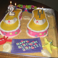 Flip Flop Cake Fondant shaped crab, beach blanket, straps; white choc seasshells and graham cracker crumbs for sand effect. Cake is buttercream.