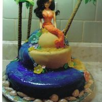 Hawaii Fantasy Three tier cake with fondant icing, flowers and seashells. Palm trees are large pretzel sticks with fondant leaves. Water is piping gel and...