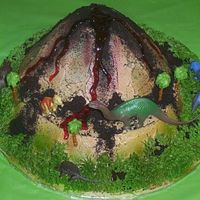 Dinosaur Volcano Buttercream volcano. Airbrushed colors on white buttercream. oreo cookie crumbs spread around. red gel for lava. the dinosaurs are plastic...