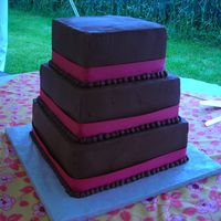 Chocolate Buttercream 12", 10", 8" square. Chocolate sour cream cake with seedless raspberry filling. Chocolate buttercream with pink ribbon.
