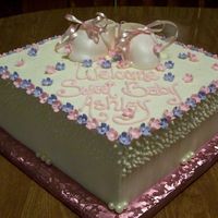 Baby Girl Buttercream icing with fondant flowers & booties. White chocolate pearls around bottom.