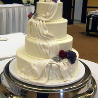 Youseffi Wedding Four tiers in buttercream with fondant swags, white fondant flowers with added real flowers. Bride supplied pins (bling) and "R"...