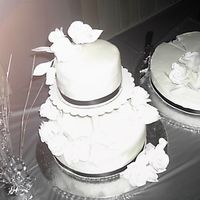 Tiered Wedding Cake White with buttercream covered in fondant, tiered, black ribbons and white flowers.