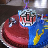Transformer Cake The cake is made from a 12" round pan covered with buttercream icing. The tranformer logo is made from MMF and colored with edible...