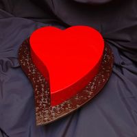 A Simple Heart An 11 inch heart shaped white chocolate coconut cake, covered in red fondant, on a textured, black fondant board.