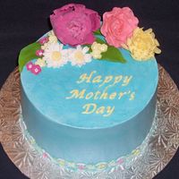 Mother's Day Cake French vanilla cake with raspberry filling covered in IMBC, flowers made of cold porcelain and gumpaste. Trellis border made of gumpaste.