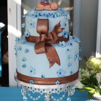 Baby Blue Covered in fondex with fondex flowers and bow. The baby is marzipan with a fondex argyle golfers hat.