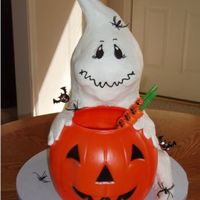 Greedy Ghost WASC cake iced in buttercream. Ghost is sitting behind trick or treat bucket holding on to it, tail of ghost comes around side. Several 8&...