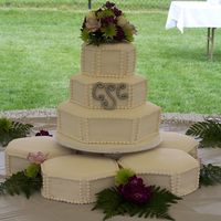 Hexagon Wedding Cake With Satellites 3 tier hexagon wedding cake on top of 5 hexagon sattelite cakes. Gumpaste monogram and fondant pearls.