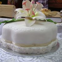 Engagement Gift this is a date cake covered in white-coloured rolled fondant, decorated with store-bought gumpaste flowers and ribbon/lace